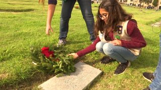 Girl is seen placing a wreath on Veterans tombstone