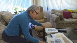 Woman in a blue sweater sits on a couch looking at pictures