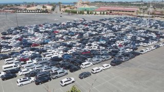 Hundreds of cars are parked close together in a large parking lot