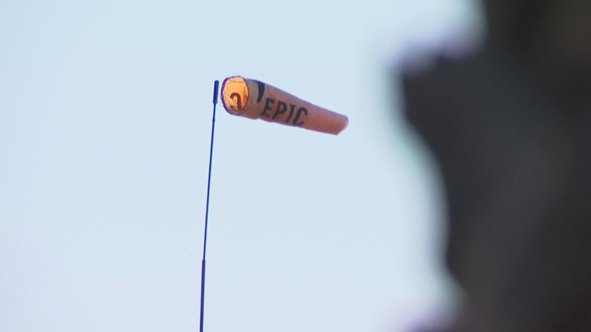 An orange wind sock with the word "epic" on the side blows behind a palm tree