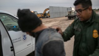 Un agente de la Patrulla Fronteriza de los Estados Unidos detiene a un inmigrante indocumentado cerca de una sección del muro fronterizo de construcción privada el 11 de diciembre de 2019 cerca de Mission, Texas.