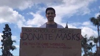 A UC San Diego medical student holds a sign during a PPE donation drive.