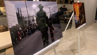 fotografía de un bombero de la mano de un niño en exposición en un tripie