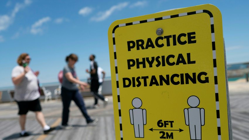 People walk past a sign advising about social distancing.