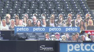 Cardboard cut-outs of people sit behind home plate at Petco Park