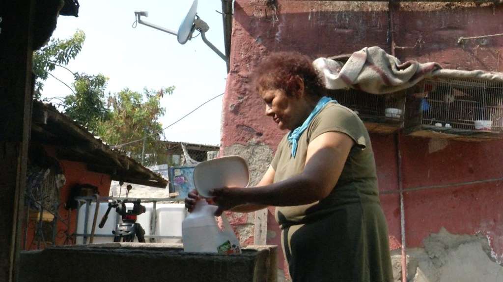 María Segovia, residente de Tijuana llena garrafones de agua en los momentos que regresa el agua a su casa para refrescarse en medio de una ola de calor que azota la región.