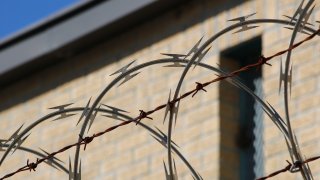 Barbed wire with a brick house in the background