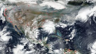 A NASA satellite image shows wildfires, heavy smoke and hurricanes.