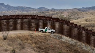 In this Feb. 9, 2019, file photo, a Border Patrol officer sits inside his car as he guards the US/Mexico border fence, in Nogales, Arizona.