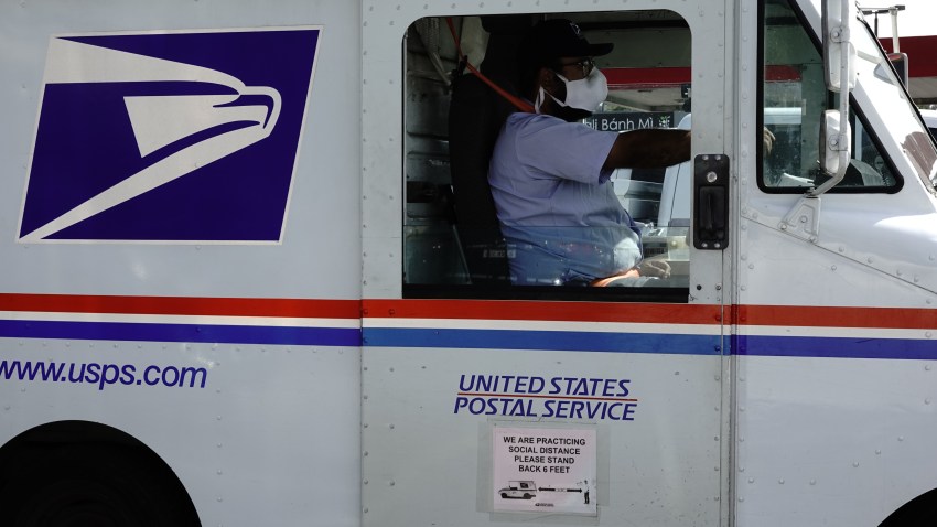 A social distancing sign is displayed on the side of a United States Postal Service (USPS) delivery truck