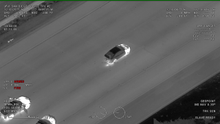 A still image taken from SDPD helicopter footage showing the suspect's car stopped on the freeway with officer vehicles close behind.