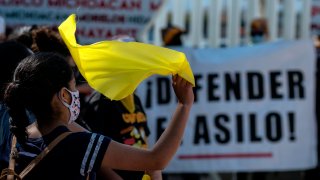 migrante con bandera amarilla protesta en la frontera