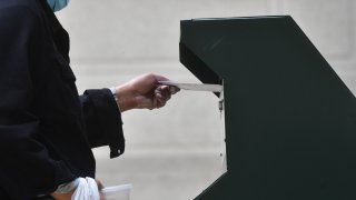 A woman deposits her ballot in an official ballot drop box at the satellite polling station outside Philadelphia City Hall on October 27, 2020 in Philadelphia, Pennsylvania.