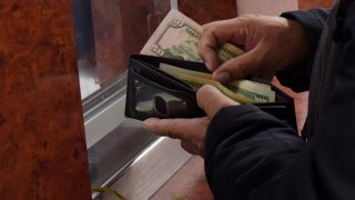 Un hombre saca dólares de su billetera para enviarlos a familiares