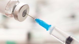 Dialing medicine into syringe from glass bottle. Ampoule and syringe needle close-up.