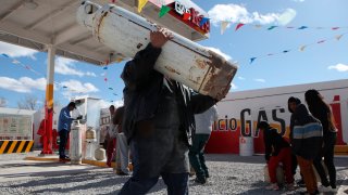 Personas hacen fila para cargar cilindros de gas