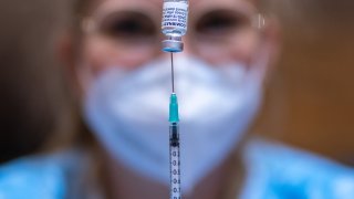 Person draws a BioNTech/Pfizer coronavirus vaccine dose into a syringe.