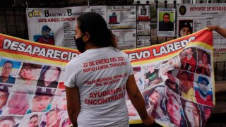 Mujer frente a una manta impresa con el rostro de desaparecidos en la frontera norte de México