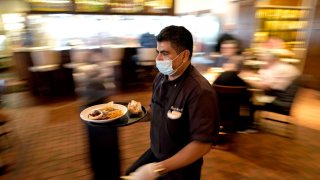 Marcelino Flores wears a face mask as he delivers food to a table at Picos restauran