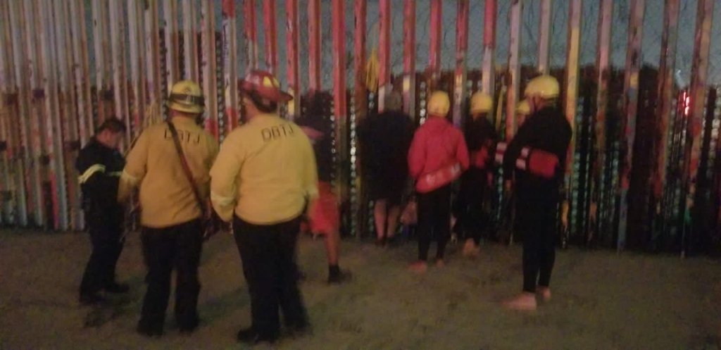 Personal de bomberos y rescate de Tijuana frente al muro fronterizo