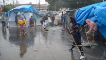 lluvias en El Chaparral niños migrantes barriendo el agua