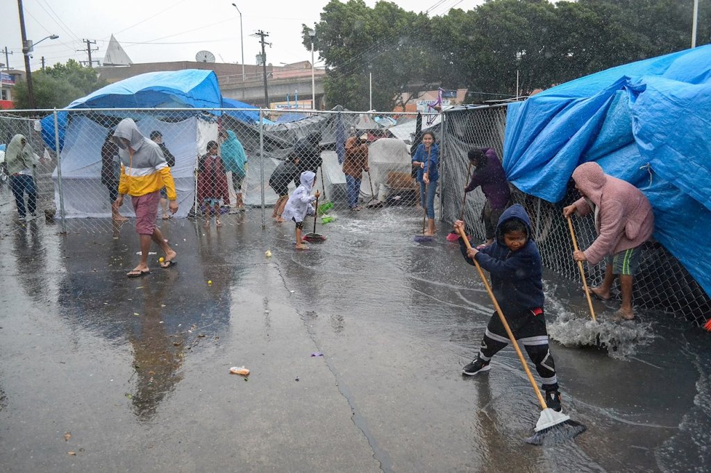 lluvias en El Chaparral niños migrantes barriendo el agua 