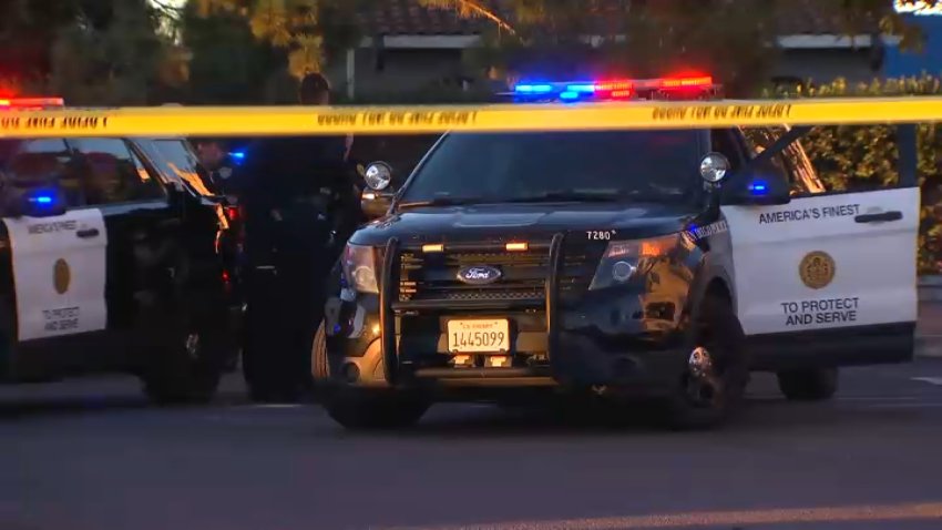 Yellow caution tape with two San Diego Police Department vehicles in the back.