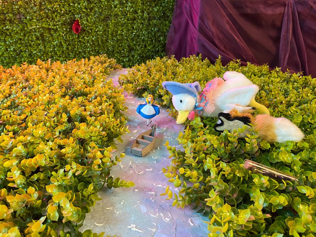 An Alice figurine rests near a stuffed animal duck, a stuffed animal fox and a vial of seeds as part of a riddle participants of The Alice - An Immersive Cocktail Experience could participate in.