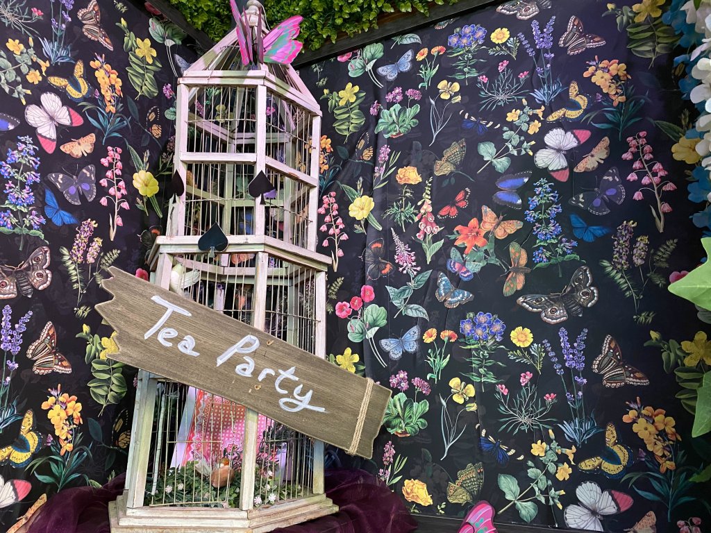 A lush, green room surrounded by butterfly backdrops sets the tone for a mad tea party.