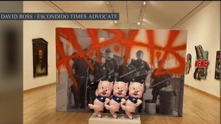 A piece at the California Center for the Arts Escondido exhibit called “Street Legacy SOCAL Style Masters," shows a line of police in riot gear behind three dancing pigs.