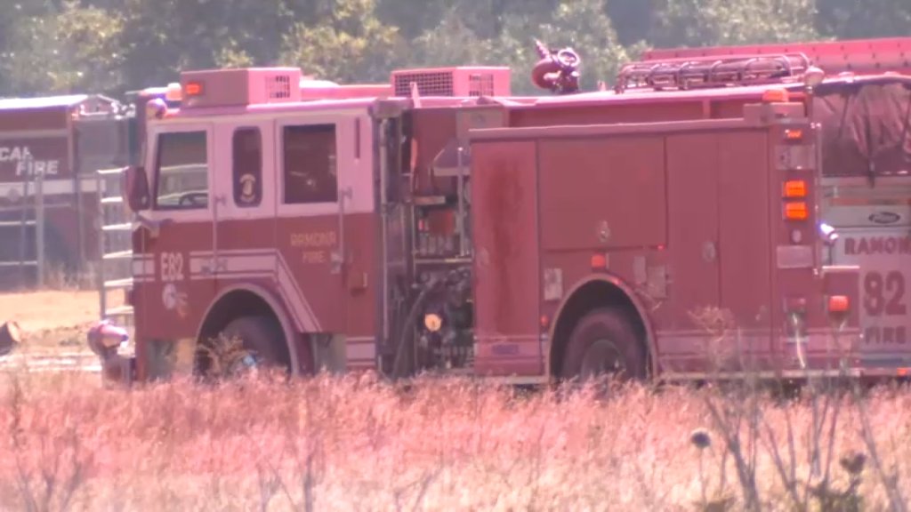 A fire truck is covered in pink fire retardant at the scene of a brush fire near the Ramona Airport on July 19, 2022.