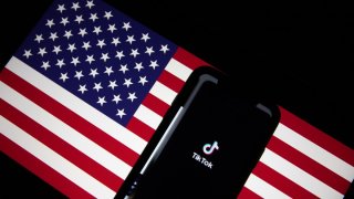 Foto de una bandera de EEUU con un teléfono y el logo de TikTok