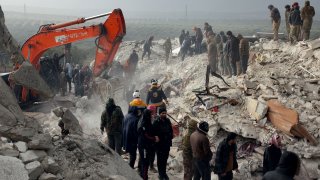 Residents and rescuers search for victims and survivors amid the rubble of collapsed buildings following an earthquake in the village of Besnaya in Syria's rebel-held northwestern Idlib province on the border with Turkey, on Feb. 6, 2023.