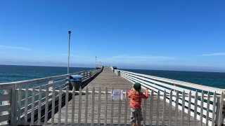 A child looks out at Crystal Pier, closed since at least early April
