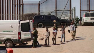 Migrantes detenidos son llevados por miembros de la Patrulla Fronteriza estadounidense a un vehículo, junto al muro fronterizo en El Paso, Texas, EEUU, en una fotografía de archivo.