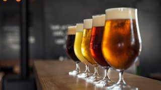 Vasos con diferentes tipos de cerveza artesanal en barra de madera. Toque cerveza en vasos de cerveza dispuestos en fila. Primer plano de cinco vasos de diferentes tipos de cerveza de barril en un pub.
