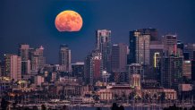 A super blue moon peeks above the San Diego skyline on Aug. 30, 2023.