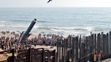 ARCHIVO - David "The Human Cannonball" Smith Jr. sale disparado sobre el muro fronterizo que divide Estados Unidos y México desde la zona conocidas como Playas de Tijuana hacia San Diego, durante un festival artístico, el 27 de agosto de 2005. (AP Foto/Denis Poroy, archivo)