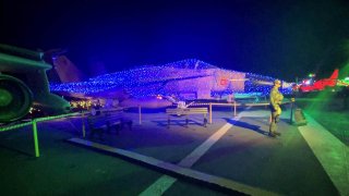 A jet is covered in holiday light aboard the USS Midway Museum flight deck for the inaugural "Jingle Jets" event in 2023.