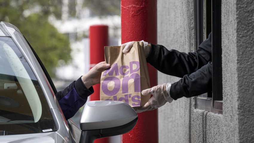 An employee hands an order to a customer through a drive-thru window at a McDonald’s restaurant in Oakland, California, April 9, 2020.