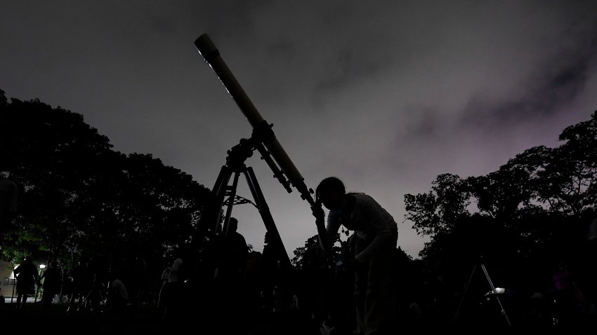 ARCHIVO – Una niña mira la luna a través de un telescopio en Caracas, Venezuela, el domingo 15 de mayo de 2022. (AP Foto/Matias Delacroix)