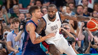 LeBron James lucha por la pelota con un jugador de Serbia este jueves, en París.