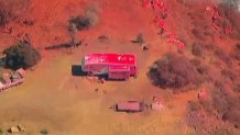 A trailer is shown covered in red fire retardant after a brush fire broke out in Valley Center, Aug. 28, 2024.