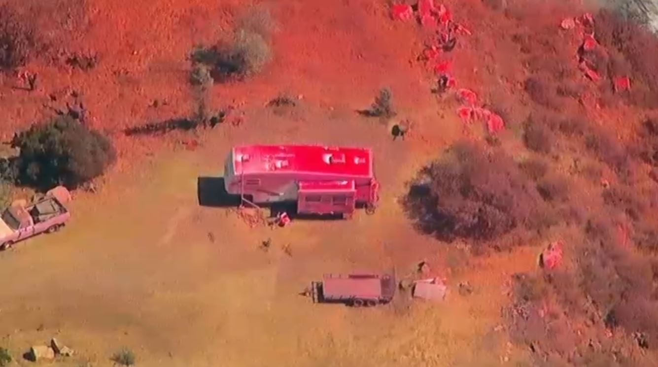 A trailer is shown covered in red fire retardant after a brush fire broke out in Valley Center, Aug. 28, 2024.