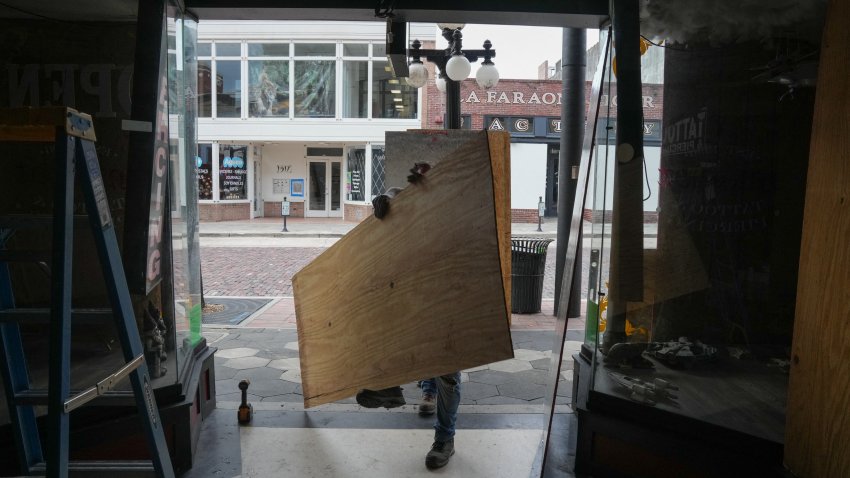 Unos contratistas colocan contrachapado sobre las ventanas de un salón de tatuajes y piercings en la zona de Ybor City de Tampa antes de que el huracán Milton toque tierra a mediados de esta semana, el 8 de octubre de 2024, en Florida. El huracán Milton aumentó su fuerza el 7 de octubre para convertirse en una tormenta potencialmente catastrófica de categoría 5 con destino a Florida, amenazando al estado estadounidense con un segundo huracán feroz en otras tantas semanas. (Foto de Bryan R. SMITH / AFP) (Foto de BRYAN R. SMITH/AFP vía Getty Images)