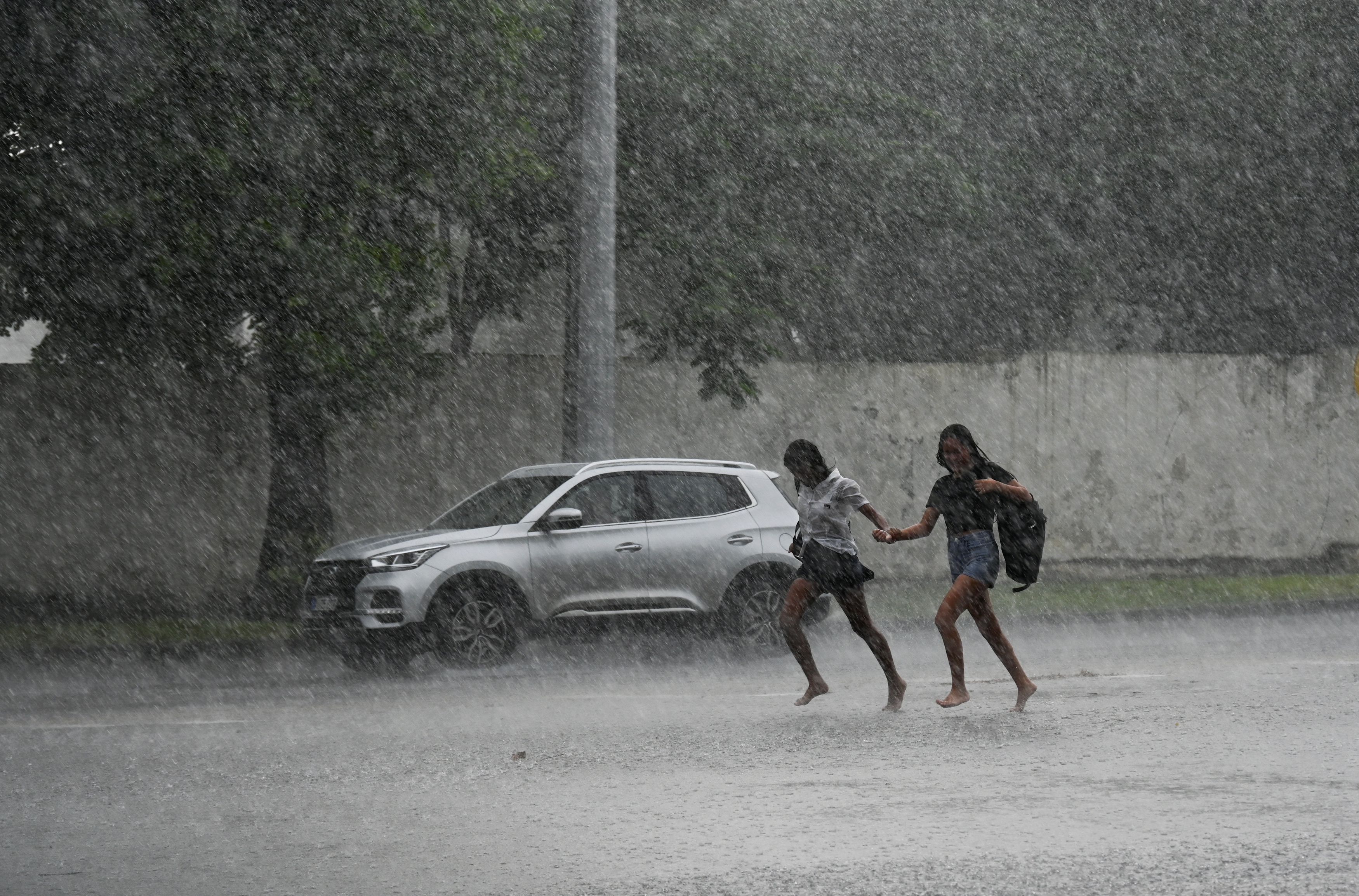 Jóvenes corren bajo una lluvia torrencial en La Habana debido al paso del huracán Milton el 9 de octubre de 2024.