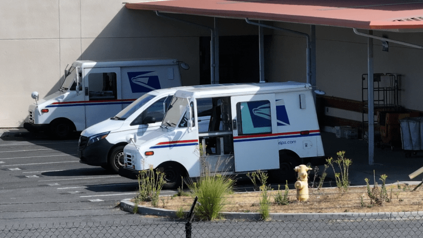 USPS vehicles await being loaded with mail at a post office in Oceanside.