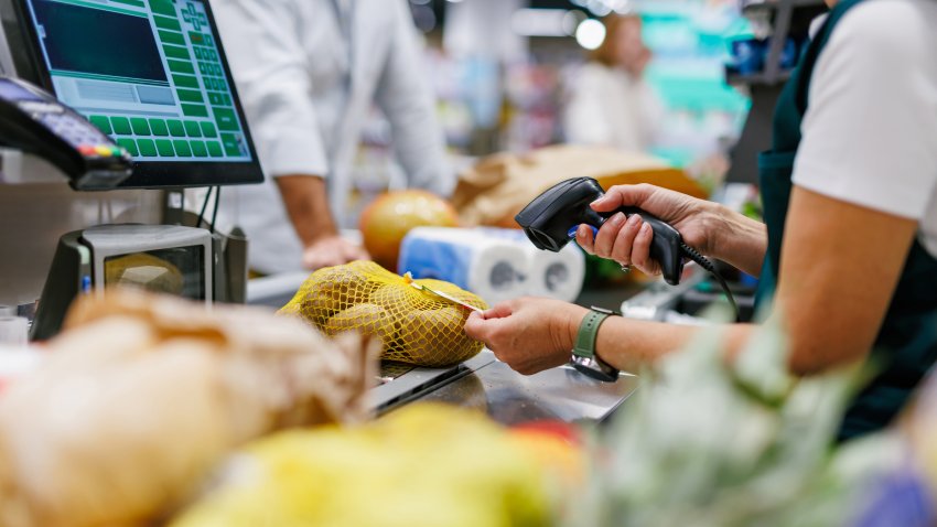 Supermarket cashier scanning potatoes at the checkout counter, processing groceries for a customer during a busy shopping day